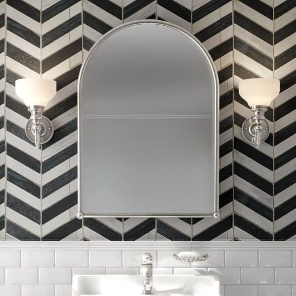 Arched Bathroom Mirror With Flanking Lights, Mounted On A Black And White Herringbone Tile Wall Above A White Subway Tile Backsplash.