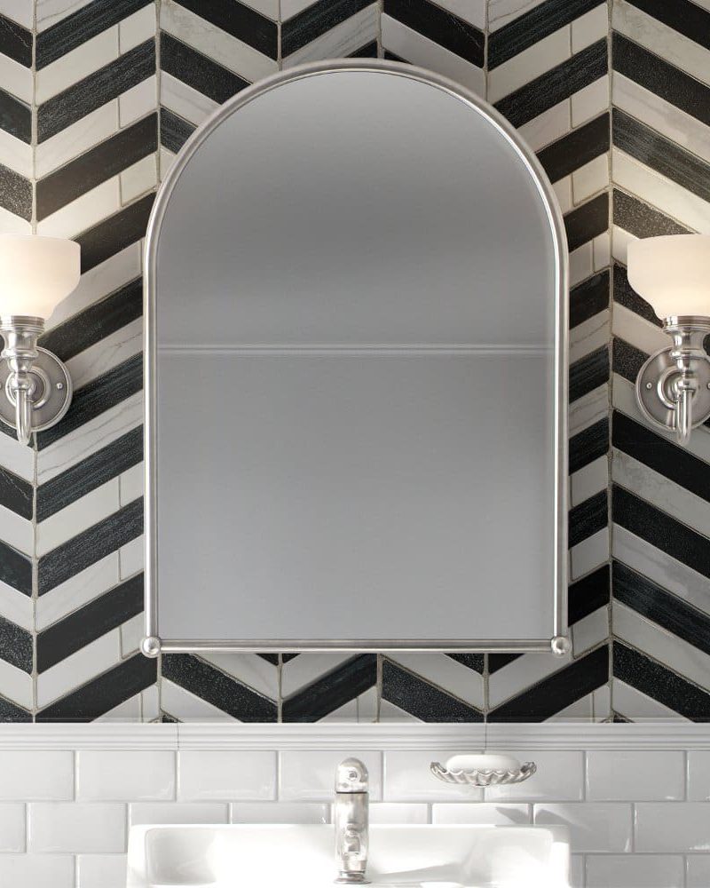 Arched bathroom mirror with flanking lights, mounted on a black and white herringbone tile wall above a white subway tile backsplash.