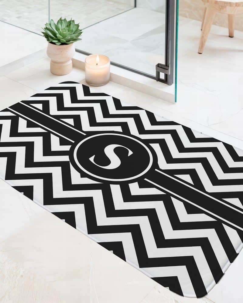 Black and white chevron patterned bath mat with a black circle and the letter S in the center.