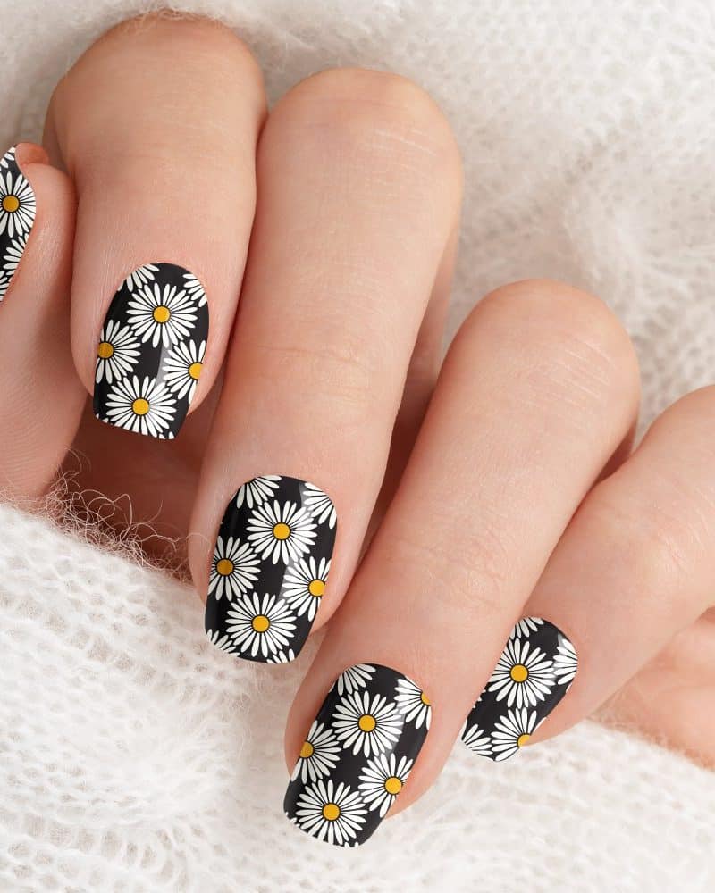 Close-up of fingernails with a black and white daisy pattern.