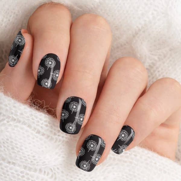 Close-Up Of A Hand With Black Nails Decorated With A White Dandelion Pattern.