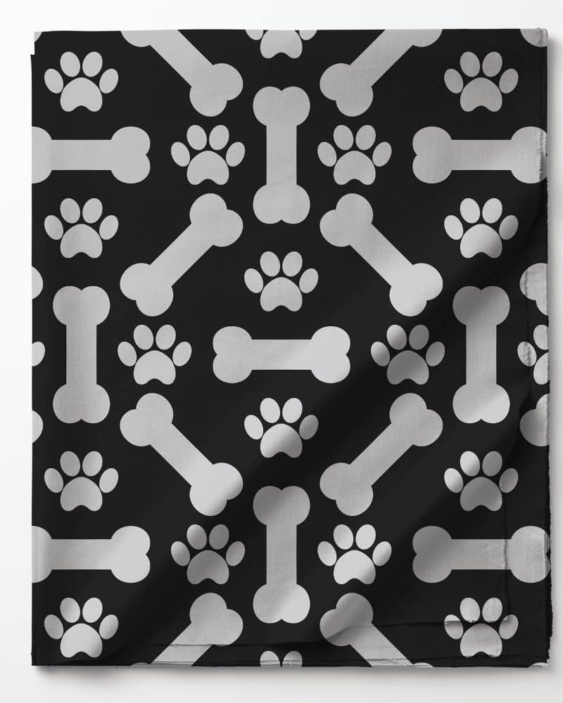Black fabric with a repeating pattern of silver bones and paw prints.