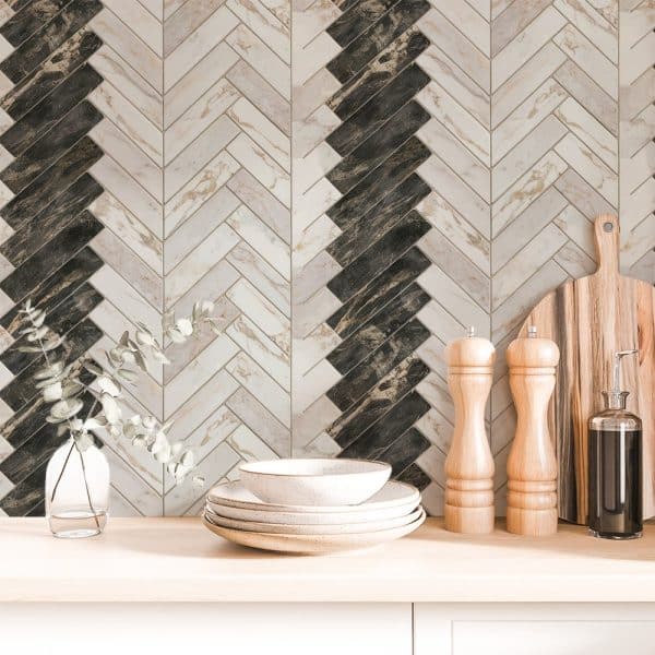 A Kitchen Counter With Stacked Dishes, Salt And Pepper Shakers, And A Cutting Board In Front Of A Herringbone Patterned Backsplash In Shades Of Beige And Dark Brown.
