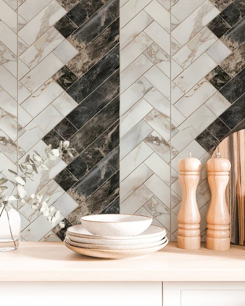 Herringbone marble tile backsplash with stacked dishes and kitchen utensils.
