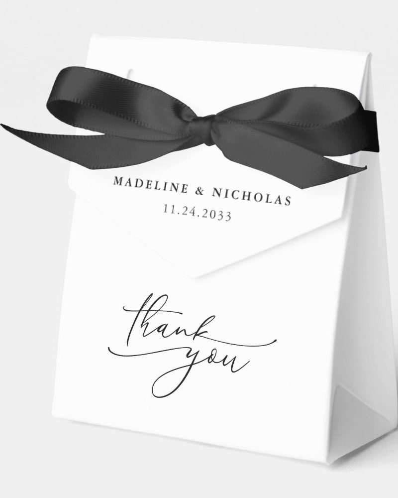 White thank you gift bag with black ribbon and Madeline & Nicholas wedding date.