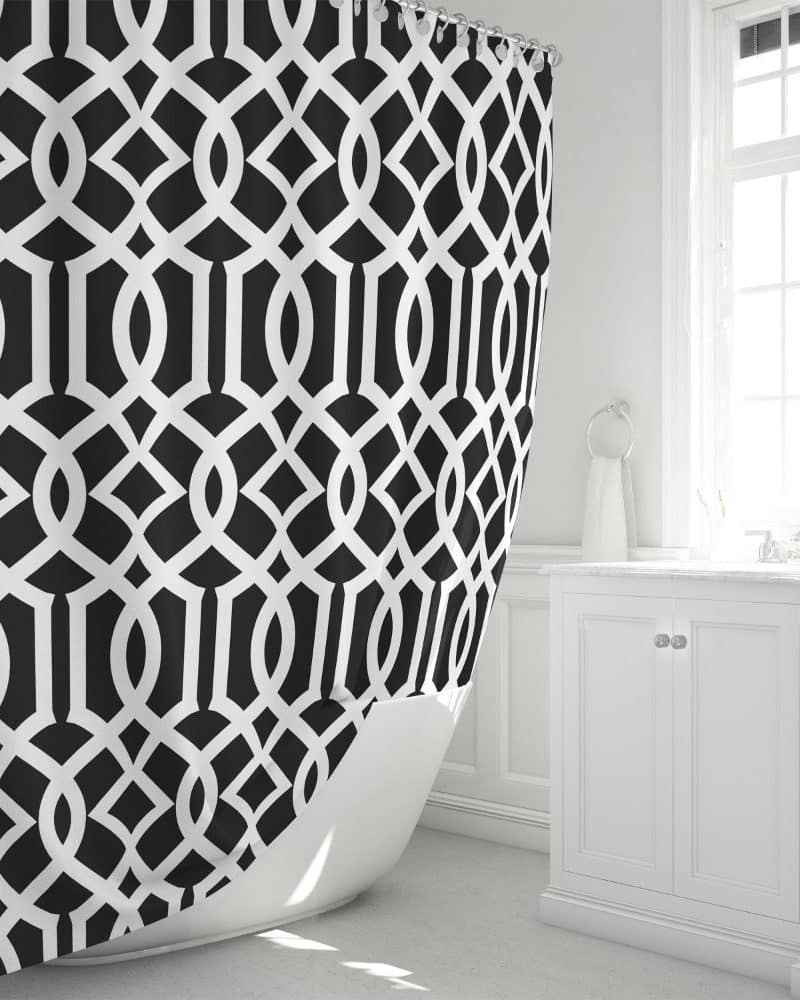 Black and white geometric patterned shower curtain draped over a white bathtub.