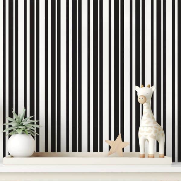 White Shelf With A Small Plant, Wooden Star, And Giraffe Toy Against A Black And White Striped Wall.