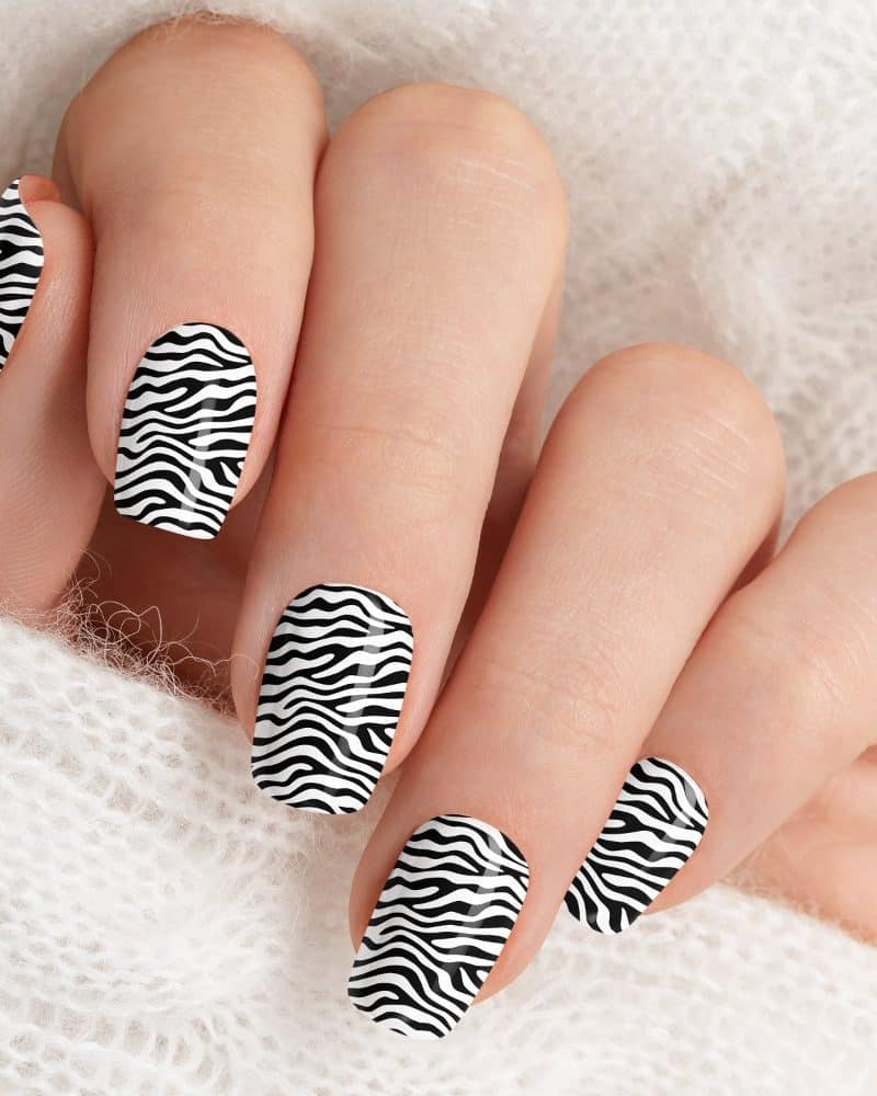 Close-up of a hand with fingernails painted in a black and white zebra stripe design.