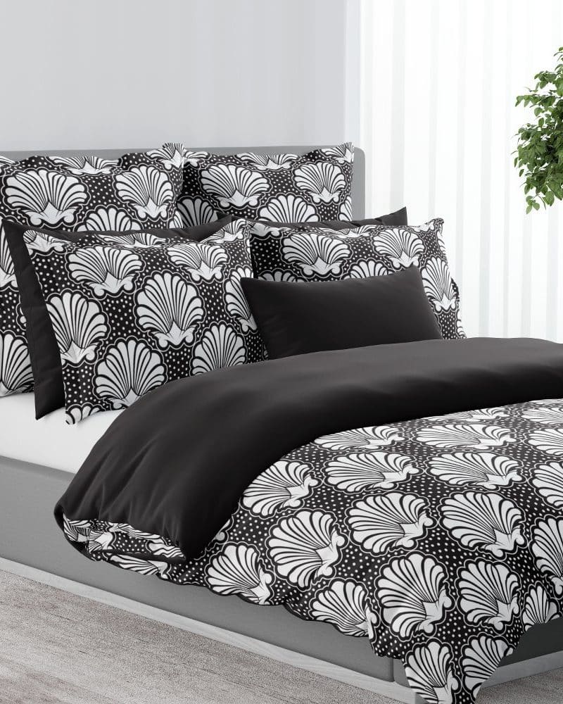 Black and white shell patterned bedding on a made bed.