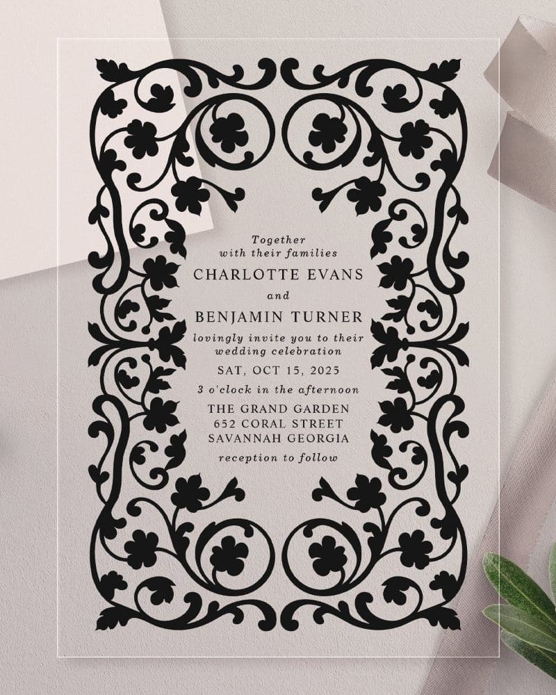 Clear acrylic wedding invitation with black ornate border and wedding details.