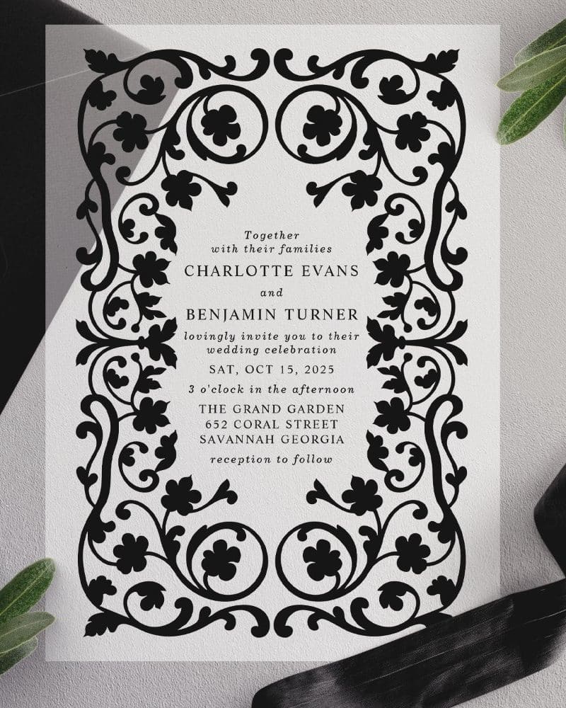 Black and white wedding invitation with ornate floral border.