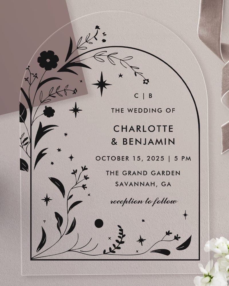 Arch-shaped clear acrylic wedding invitation with black floral and star design, announcing Charlotte and Benjamin's wedding.