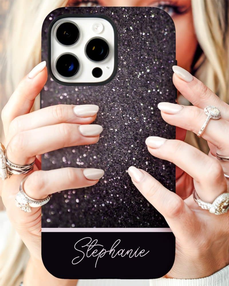 Close-up of hands holding a black glitter iPhone case with the name Stephanie on it.