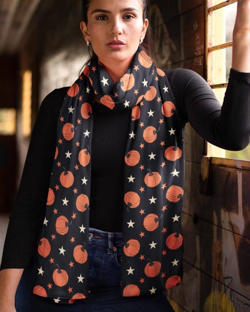 Woman wearing a black scarf with orange pumpkins and white stars.