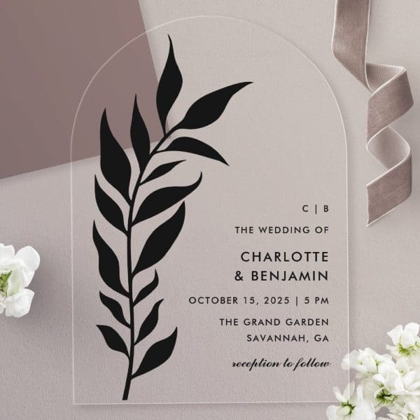 Arch-Shaped Clear Acrylic Wedding Invitation With A Black Floral Design And The Names Charlotte And Benjamin.