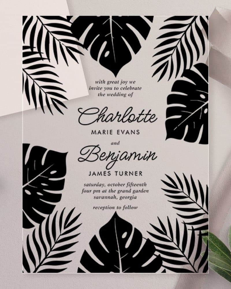 A wedding invitation with black tropical leaves on a white background announcing the marriage of Charlotte Marie Evans and Benjamin James Turner.