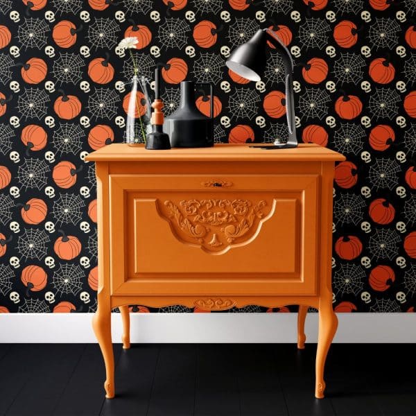 Orange Dresser With Ornate Details Against A Halloween-Themed Wallpaper.