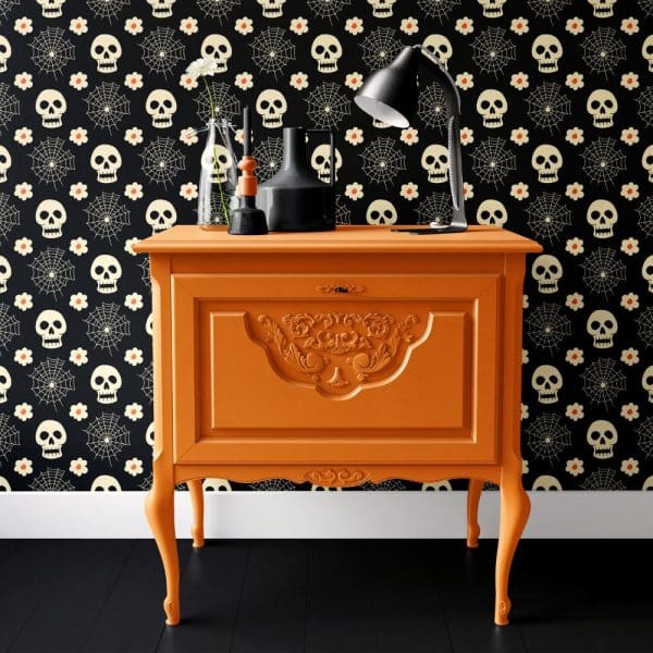 Orange Dresser With Decorative Carvings Sits Against A Wall With A Halloween Skull And Spiderweb Pattern.