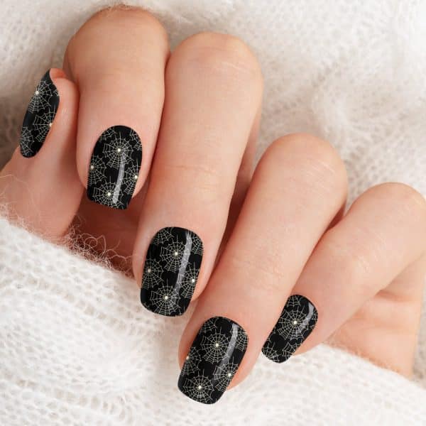 Closeup Of A Hand With Black Fingernails Decorated With A Pattern Of White Spiderwebs.