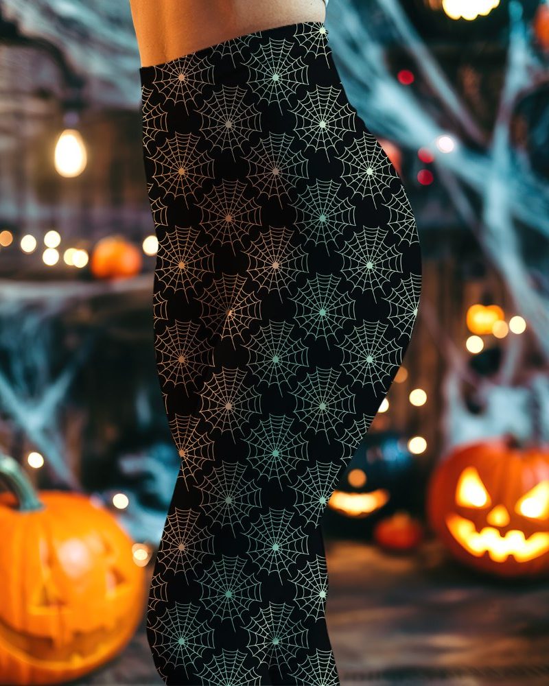 Close-up of a person's lower body wearing black leggings with a pattern of light green spiderwebs.