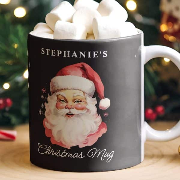 A Black Christmas Mug With A Vintage Santa Illustration, Personalized With The Name Stephanie'S, Filled With Marshmallows.