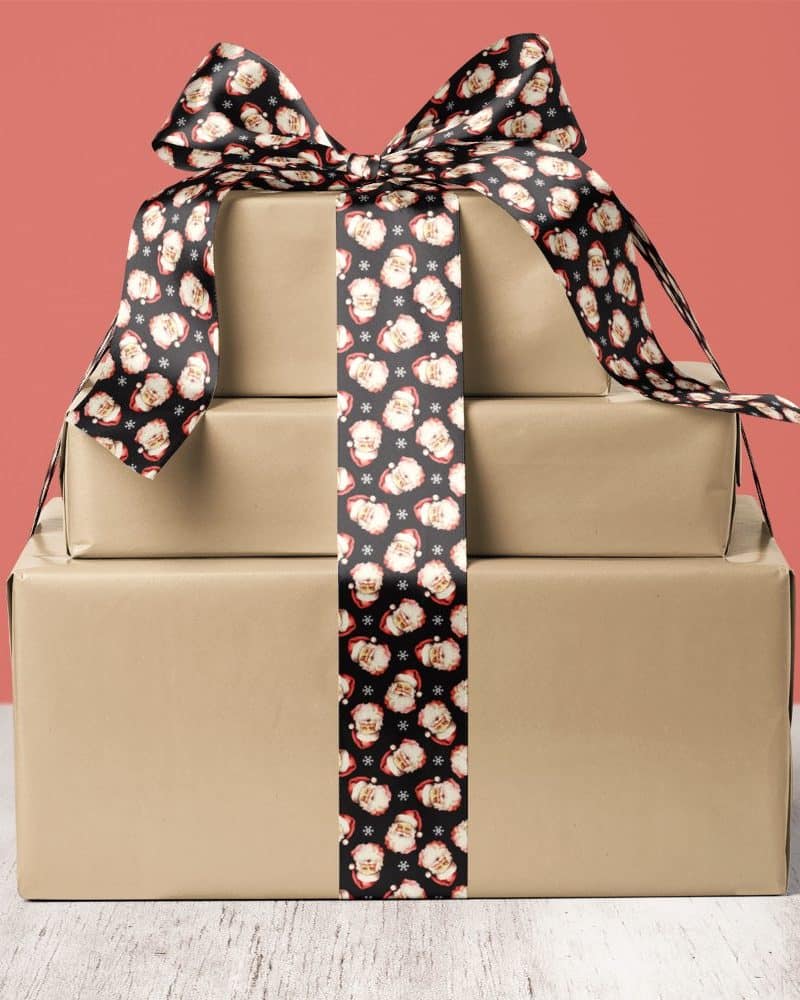 A stack of three brown gift boxes tied with a Santa Claus ribbon.