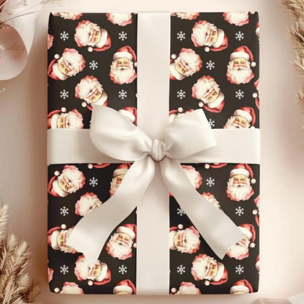 A Christmas Gift Wrapped In Dark Paper Featuring A Repeating Pattern Of Santa Claus Faces And Snowflakes, Tied With A Cream-Colored Ribbon.