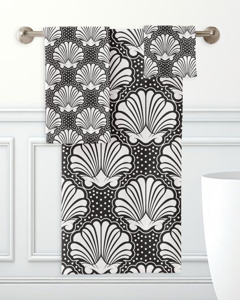 Black and white bath towels hanging on a rack, featuring a repeating seashell pattern.
