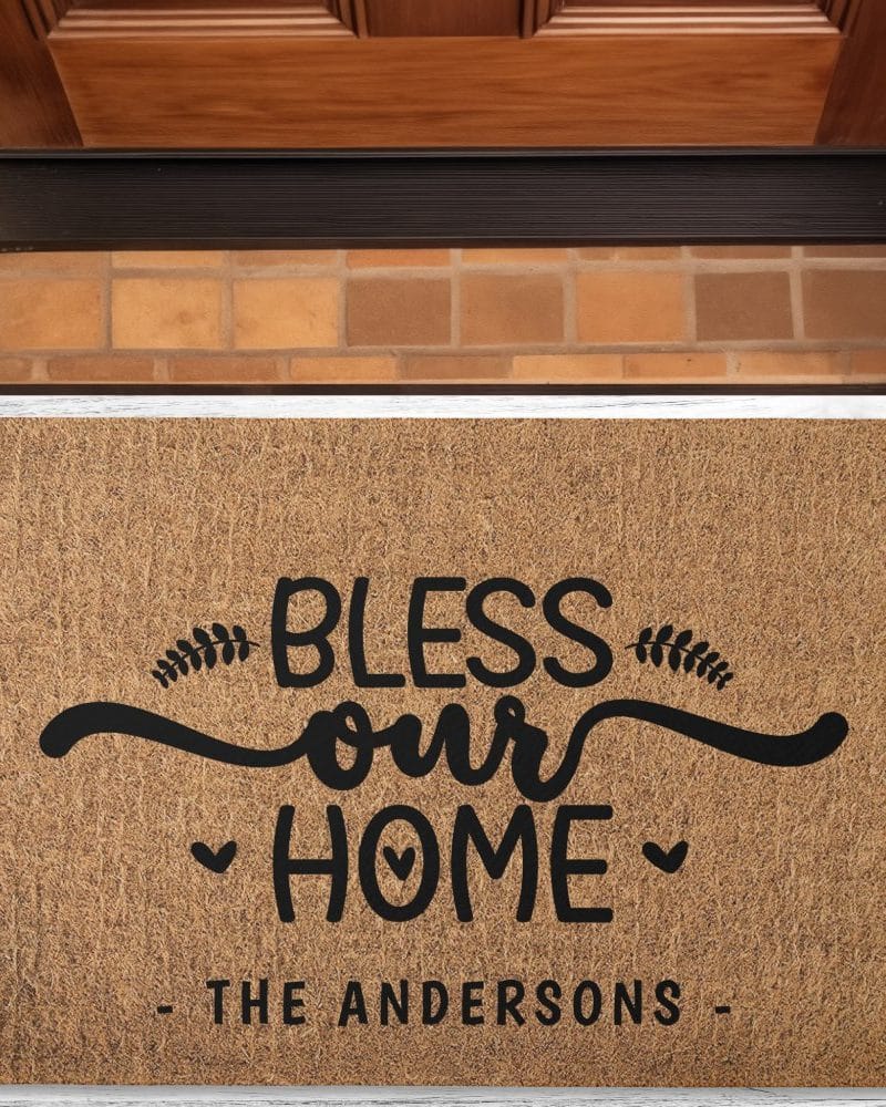 Tan doormat with black lettering that says Bless Our Home, with the family name The Andersons below.