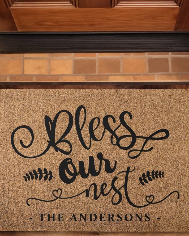 Tan doormat with black lettering that says Bless Our Nest and the Andersons family name.