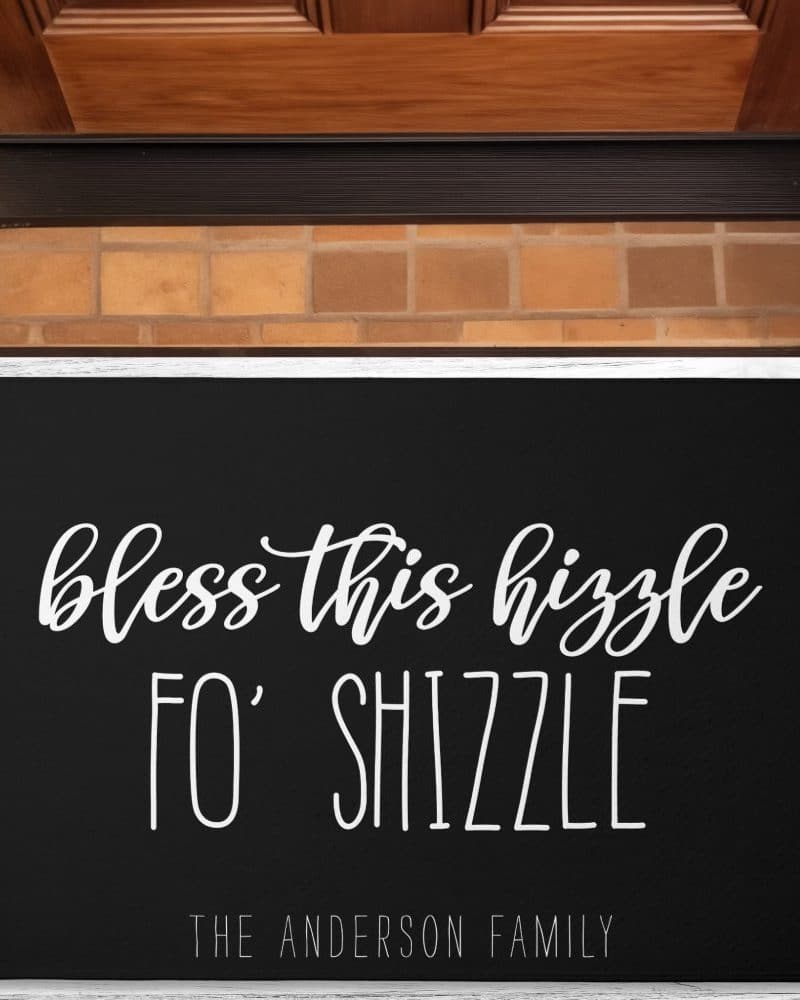 Black doormat with white cursive text reading Bless this hizzzle fo' shizzle and the Anderson Family name below.