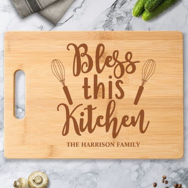 Bamboo Cutting Board With The Words Bless This Kitchen And The Harrison Family Engraved On It.