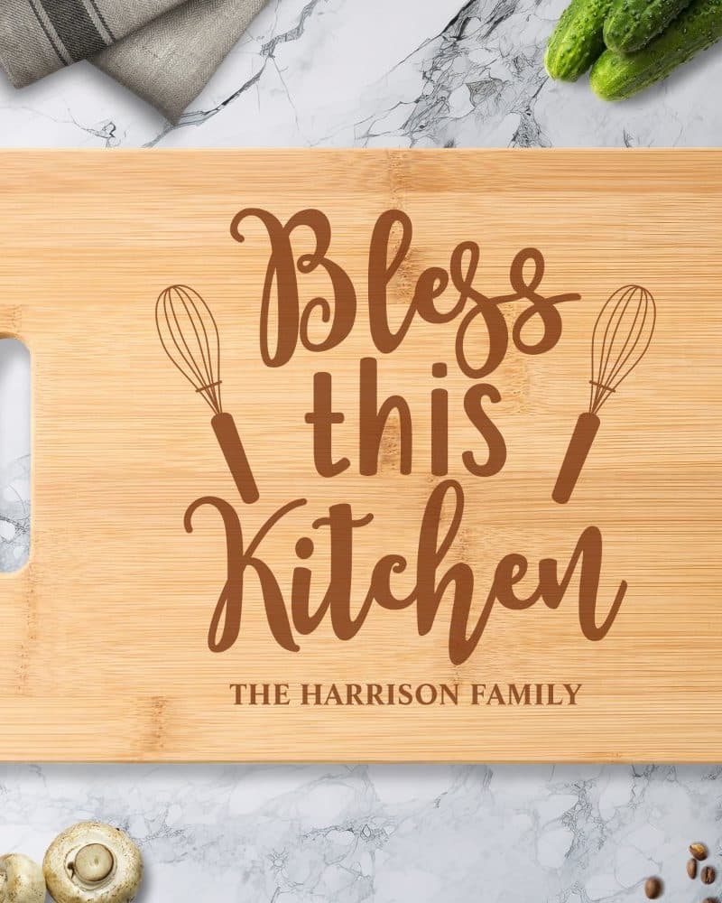 Bamboo cutting board with the words Bless this Kitchen and The Harrison Family engraved on it.