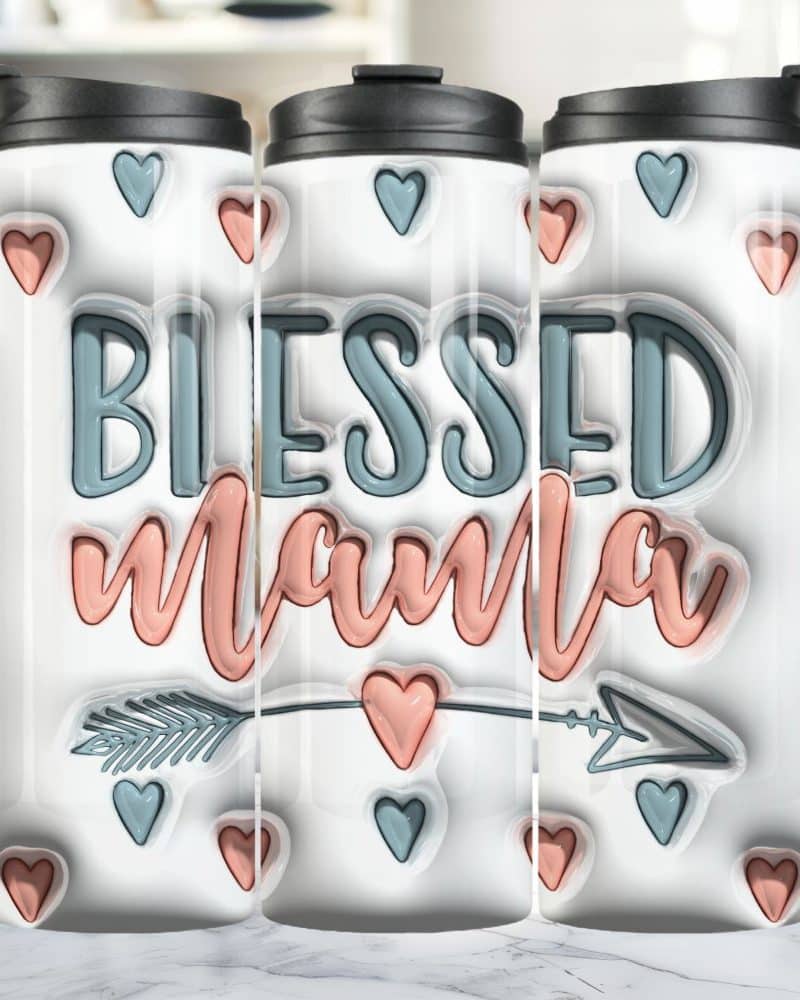 Three white travel mugs with the words Blessed Mama in teal and peach. Small hearts and an arrow are also on the mugs.