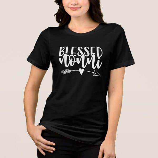 Woman Wearing A Black T-Shirt That Says Blessed Nonni In White Lettering With A Small Arrow And Heart.