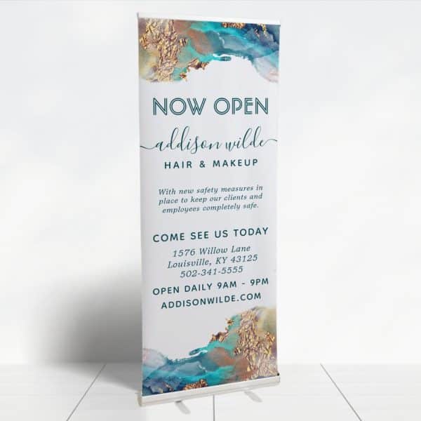 A Retractable Banner Announcing The Grand Opening Of Addison Wilde Hair &Amp; Makeup. The Banner Features Teal And Gold Abstract Artwork.