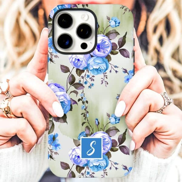 A Woman'S Hands Holding A Phone Case Featuring A Floral Pattern Of Blue Roses On A Light Green Background. A Blue Initial S Is In The Lower Center.