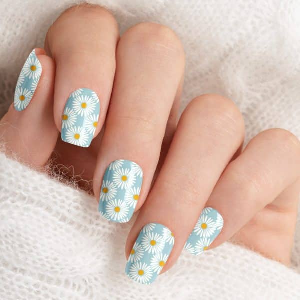 Closeup Of A Hand With Light Blue Nails Decorated With A Daisy Pattern.