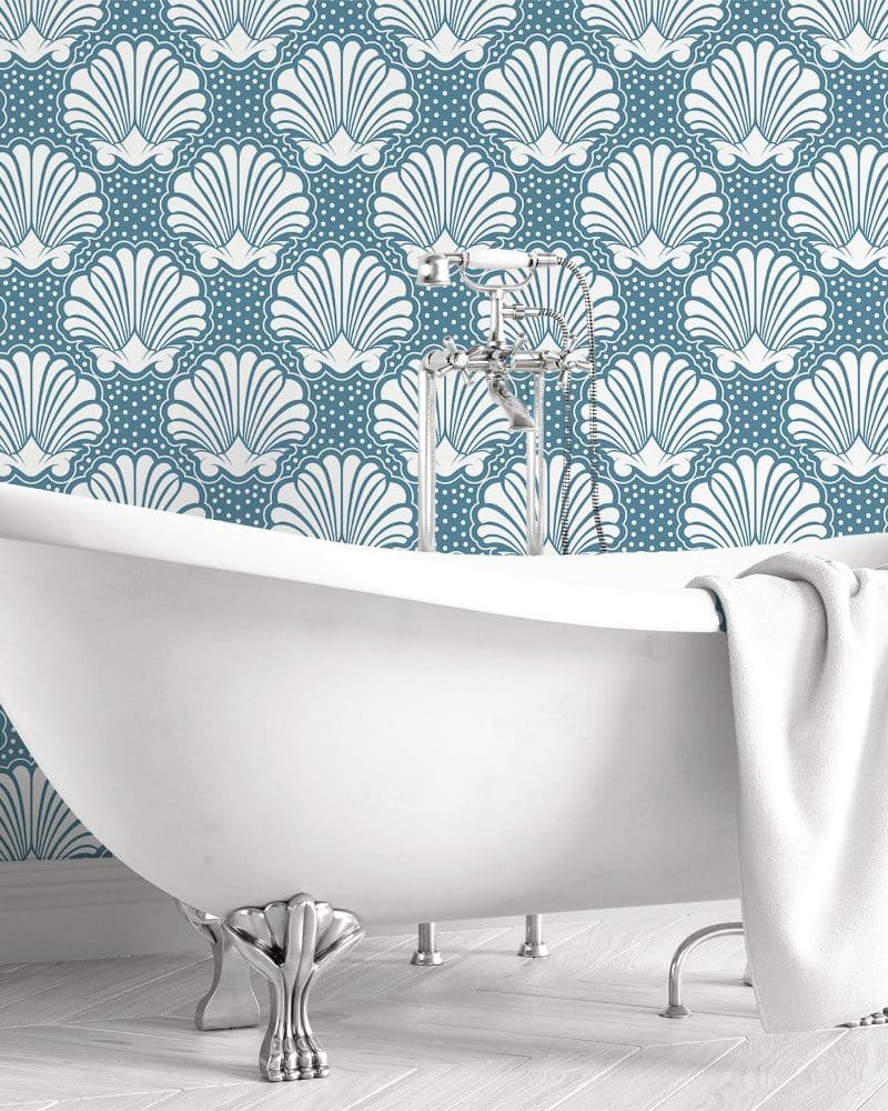 White clawfoot bathtub in front of a teal seashell patterned wall.
