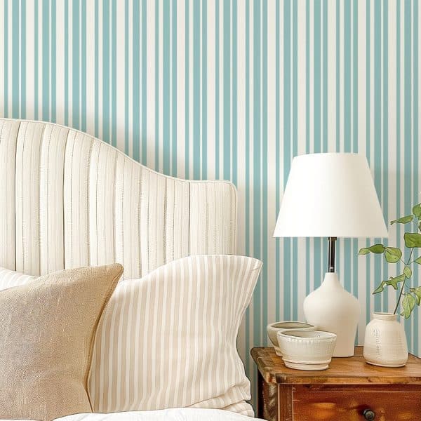 Beige Headboard With Pillows Against A Wall With Vertical Blue And White Stripes.