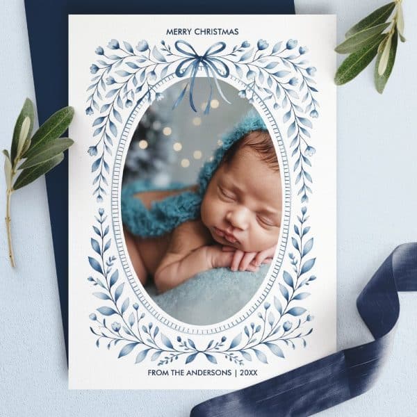Christmas Card Featuring A Sleeping Baby In A Blue Bonnet, Framed By A Blue Floral Design.