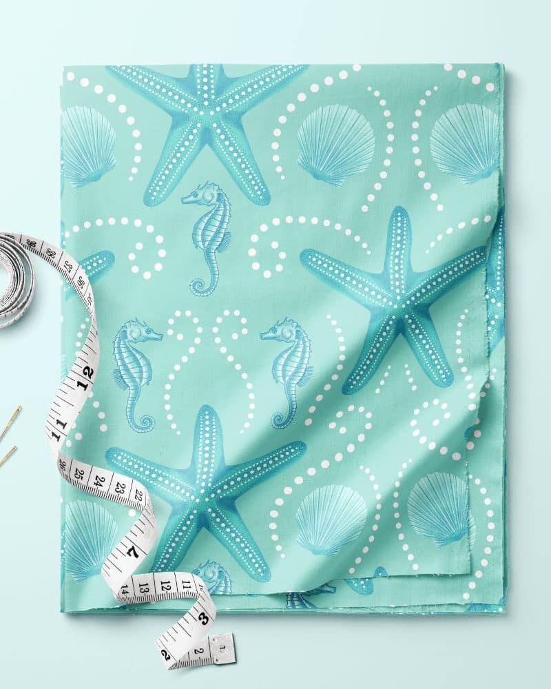 Light teal fabric with a pattern of starfish, seahorses, and seashells.