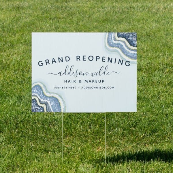 A Yard Sign Announcing The Grand Reopening Of Addison Wilde Hair &Amp; Makeup. The Sign Features A Blue And Gold Agate Design.