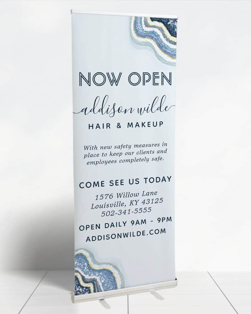 Retractable banner announcing the grand opening of Addison Wilde Hair & Makeup salon, including address and hours.
