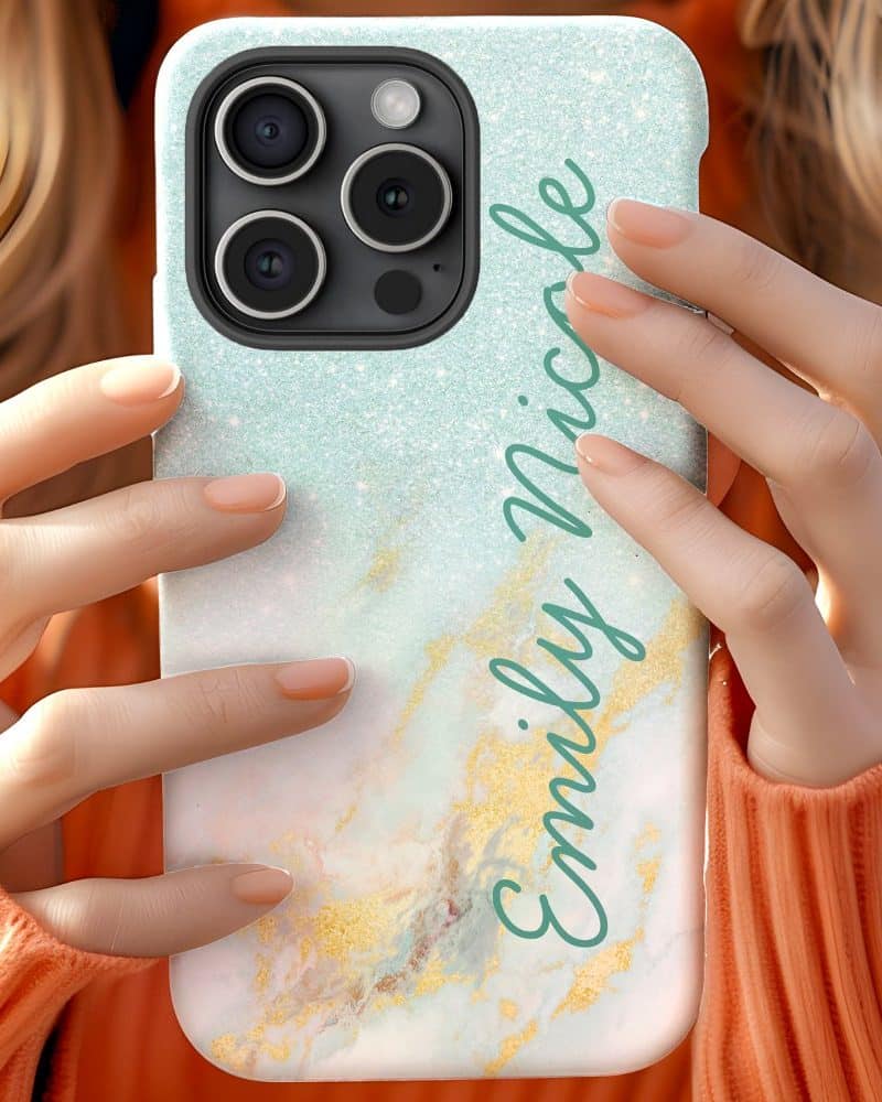 A woman's hands holding a teal and gold marbled iPhone case with the name Emily Nicole written on it.