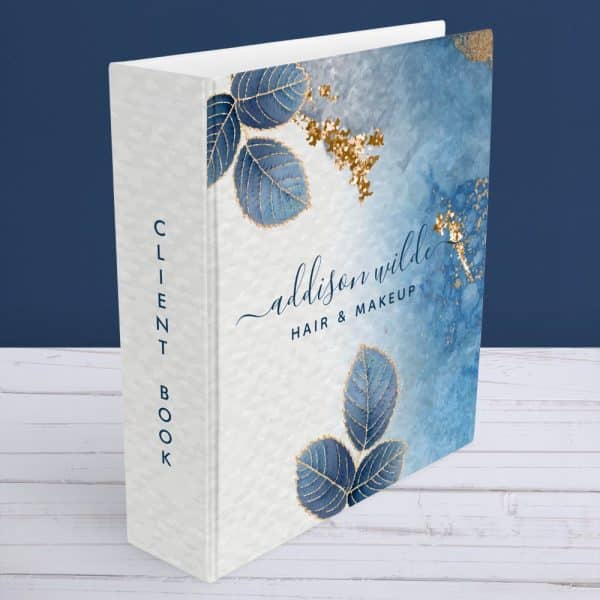 A White Client Book For Addison Wilde Hair &Amp; Makeup, Featuring Blue Leaves With Gold Accents On A Blue And White Watercolor Background.