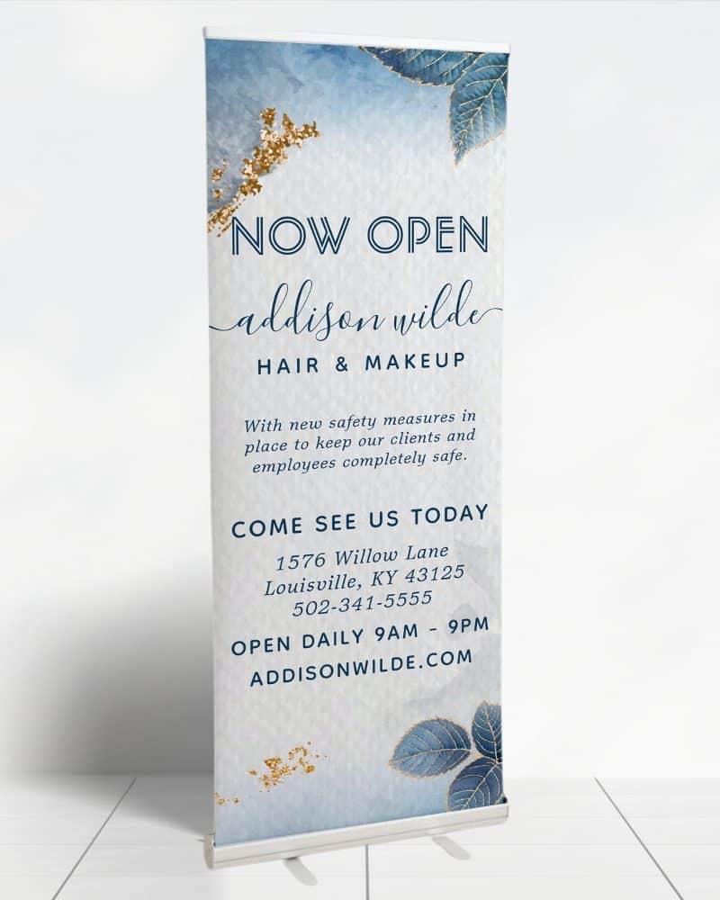 Retractible banner announcing the grand opening of Addison Wilde Hair & Makeup salon, including address and hours.