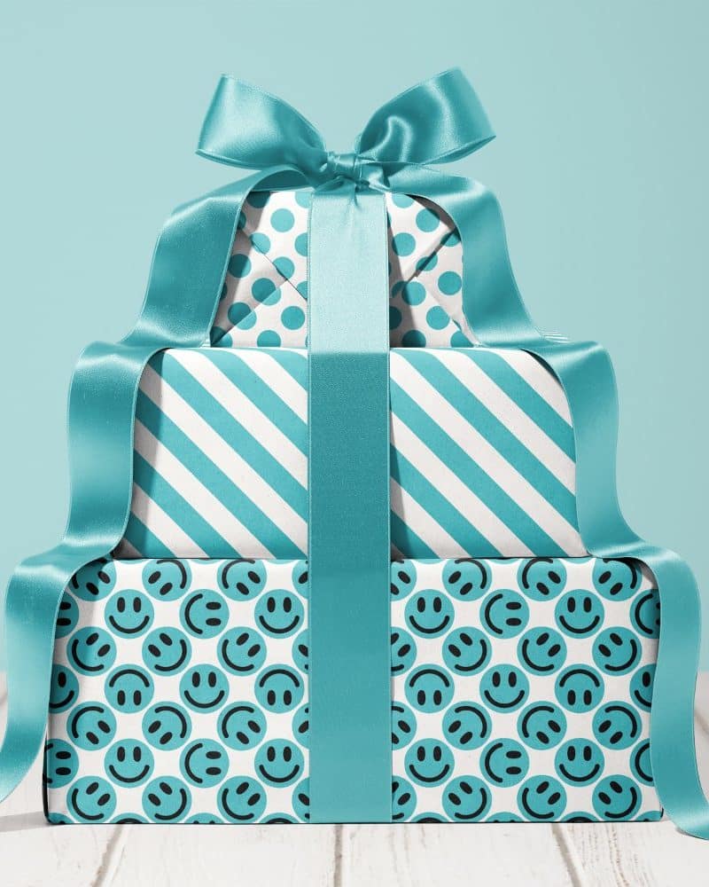 Stack of three teal wrapped presents with a large teal ribbon. The boxes feature different patterns.