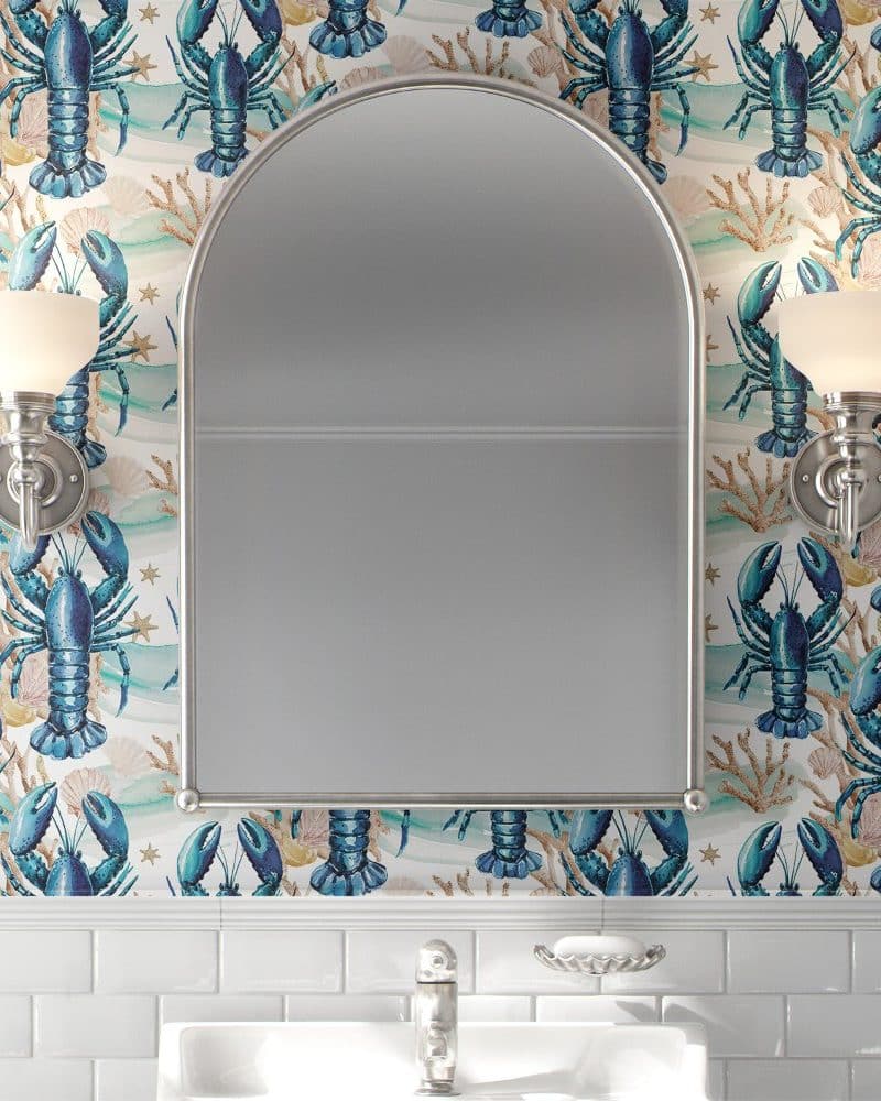 Bathroom mirror with arched top, flanked by wall-mounted lights, all set against a wall covered in wallpaper featuring a repeating pattern of blue lobsters and seashells.