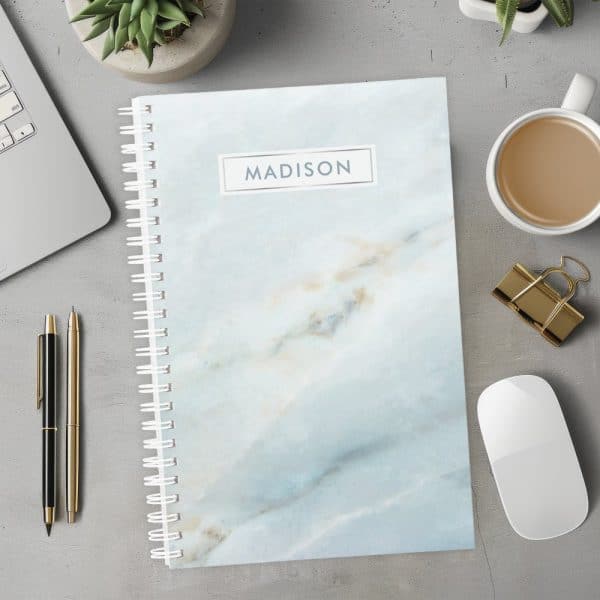 Spiral-Bound Notebook With A Light Blue Marble Design And The Name Madison On The Cover.